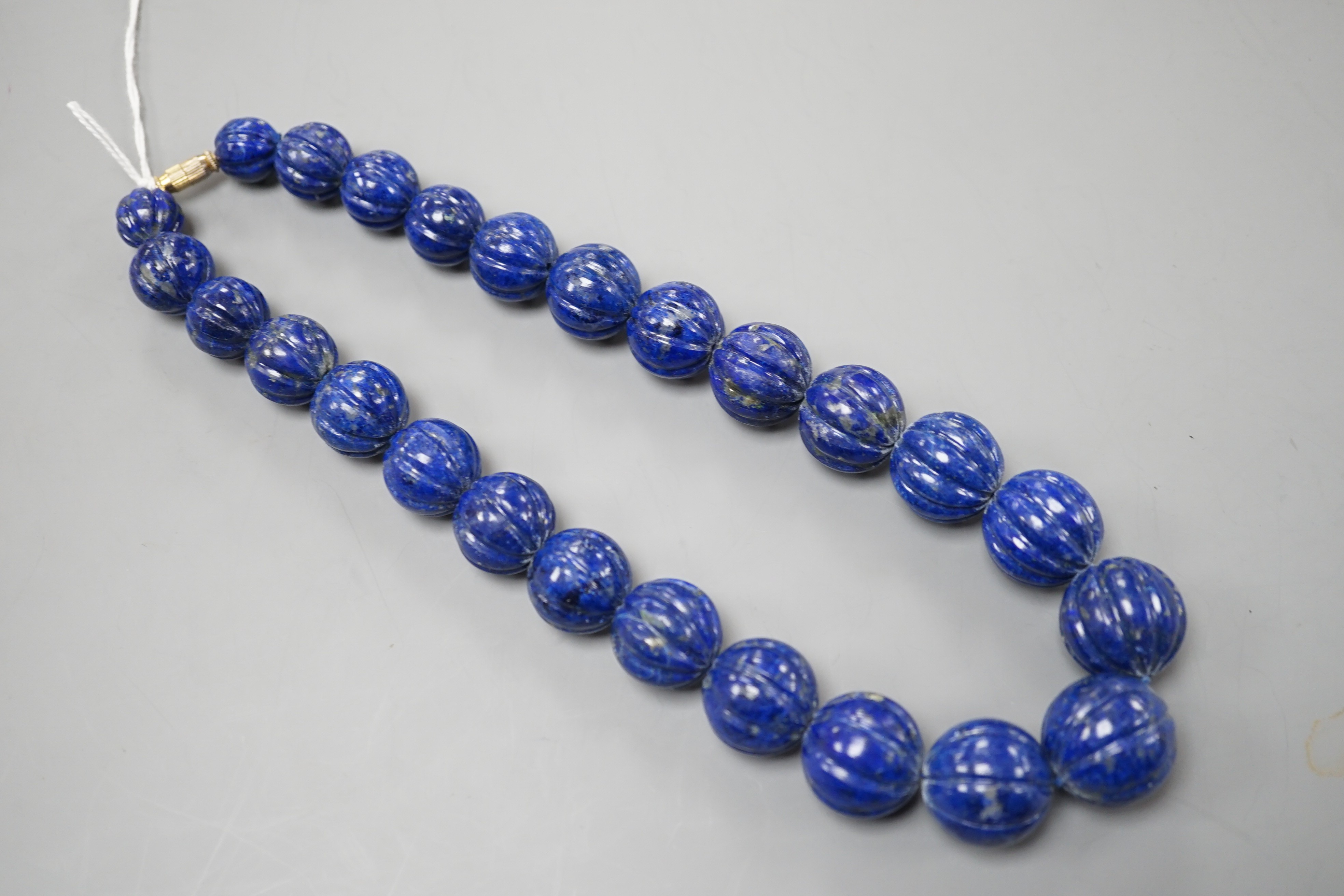 A single strand graduated fluted lapis lazuli bead necklace, 44cm